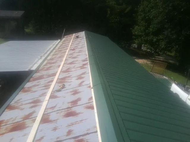 Old rusted panels beside newly installed green metal roofing — Wind Damage Roof Repair by Roofing Brothers in Jefferson City