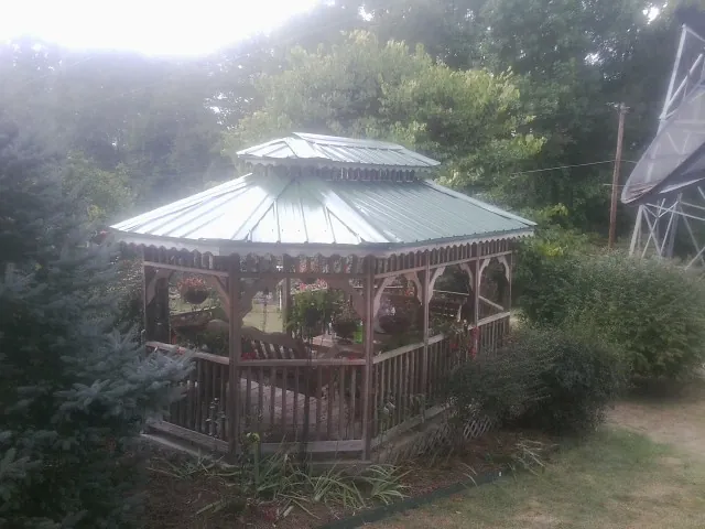 Green metal roof on a backyard gazebo surrounded by garden beds in Jefferson City