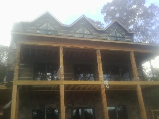 Dormers and porch framing on a large log home under construction — Roof Coating work by our crew in Jefferson City